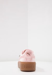 Różowy sneaker Puma z gumową podeszwą, widziany od tyłu, z logo Puma na pięcie i podeszwie platformowej.