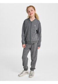 Grå zip-up sweatshirt och matchande joggers i mjukt, texturerat tyg, med ribbade ärmslut och en liten logotypaccent på vänster bröst.