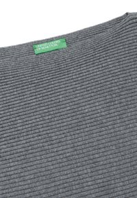 Camicia grigia con texture caratterizzata da tessuto a coste orizzontali, con un'etichetta verde che riporta "UNITED COLORS OF BENETTON" vicino al colletto.