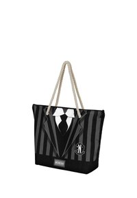 Sac fourre-tout noir avec un design rayé ressemblant à un smoking, doté d'une poignée en corde et d'un badge avec 'N'. Le matériau semble durable et synthétique.