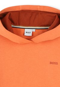 Sweat à capuche orange en tissu doux. Présente une étiquette de logo et une doublure intérieure contrastante. Comprend un col en côtes et une coupe générale décontractée.