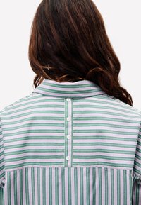 Grün-weißer, gestreifter Hemd mit Kragen, Knopfverschluss im Nacken und lässiger Passform. Fein gewebte Textur mit unterschiedlich breiten Streifen.