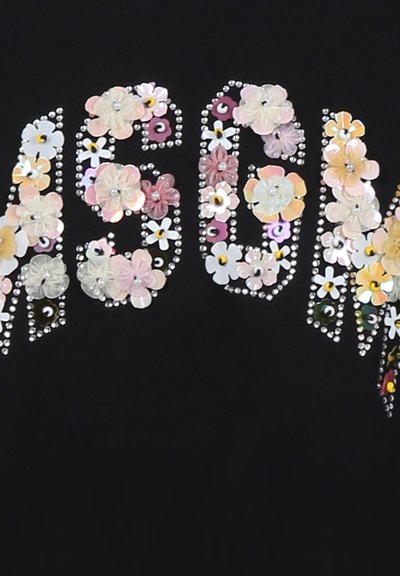 Testo su fondo nero con "1990" decorato da applicazioni floreali multicolori e strass, creando un design decorativo e testurizzato.