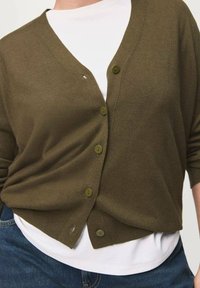 Green knitted cardigan with a V-neck, featuring six buttons, three-quarter sleeves, and a relaxed fit over a white T-shirt.