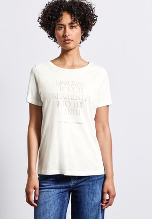 Cotton t-shirt in off-white with a round neckline, short sleeves, and raised text design stating "NATURAL TOUCH BREATHES LIFE INTO THE EARTH."