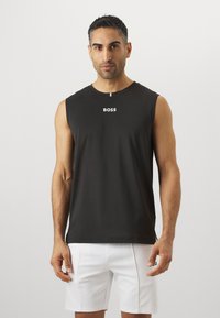 Juodas be rankovių marškinėlis su apvaliu kaklu ir baltu "BOSS" logotipu, esančiu centriniame krūtinės regione. Lygus audinys be matomų raštų ar akcentų.