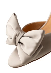 Beige satiini liukusandaali, jossa on suuri nauha etupuolella, avoin varvastyyppi ja sileä sisustus hienovaraisella tekstuurilla.