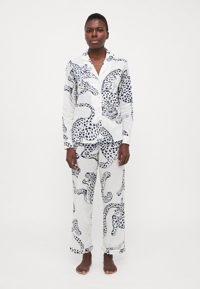 Witte katoenen pyjama set met een blauw luipaardprint, bestaande uit een overhemd met knopen en loszittende broek, lange mouwen en een borstzak.