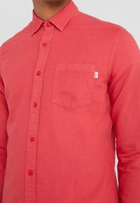 Rode button-up overhemd van lichtgewicht stof. Heeft een enkele borstzak en contrasterende knoopkleuren. Slim fit met een gestructureerde kraag.