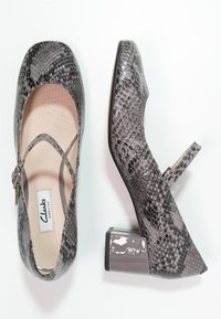 Šedé lodičky se vzorem hadí kůže, zaoblenou špičkou a ankletovým páskem. Mají lesklý blokový podpatek a hladký povrch uvnitř.
