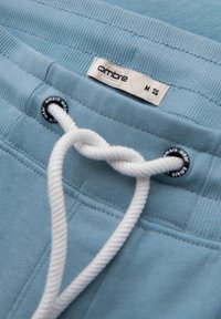 Lichtblauwe joggingbroek van textuurstof, met een witte trekkoord en metalen sluitingen. Label zegt "ombre", maat M.