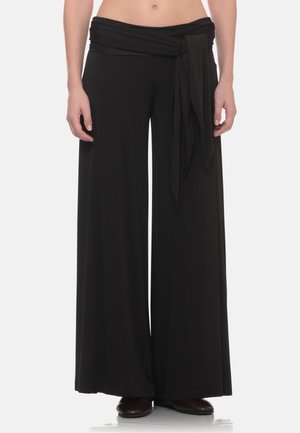 Pantaloni neri a gamba larga con vita alta e dettaglio di cintura in tessuto annodato, indossati con scarpe nere.