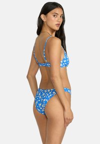 Blue floral bikini set featuring thin straps and a high-cut bottom. Fabric has a smooth texture with a pattern of white and yellow flowers.