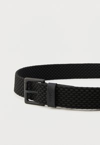 Μαύρη υφασμάτινη ζώνη με υφαντό σχέδιο, με ματ μαύρη πόρπη και μαύρο δερμάτινο λουράκι με τη μάρκα "HUGO" σε λευκό φόντο.