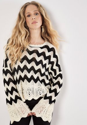 Gestreifter, schwarzer und cremfarbener, gestrickter Pullover mit Zickzackmuster, offenem Strickmuster, rundem Ausschnitt und weiten Ärmeln. Lässiger, lockerer Schnitt.