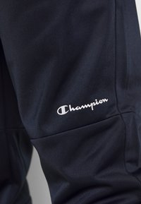 Svarta träningsbyxor i texturerad tyg med en åtsittande design. Har en vit "Champion"-logotyp på det nedre benet.