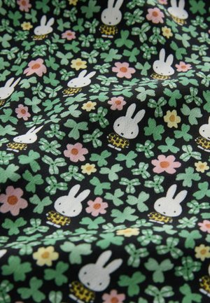 Black fabric featuring a repeated pattern of white rabbits, flowers in pinks and yellows, and green clovers with plaid accents.
