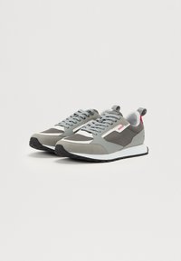 Grey athletic shoes with a combination of smooth and textured materials. Features a white midsole and red accent on the heel.