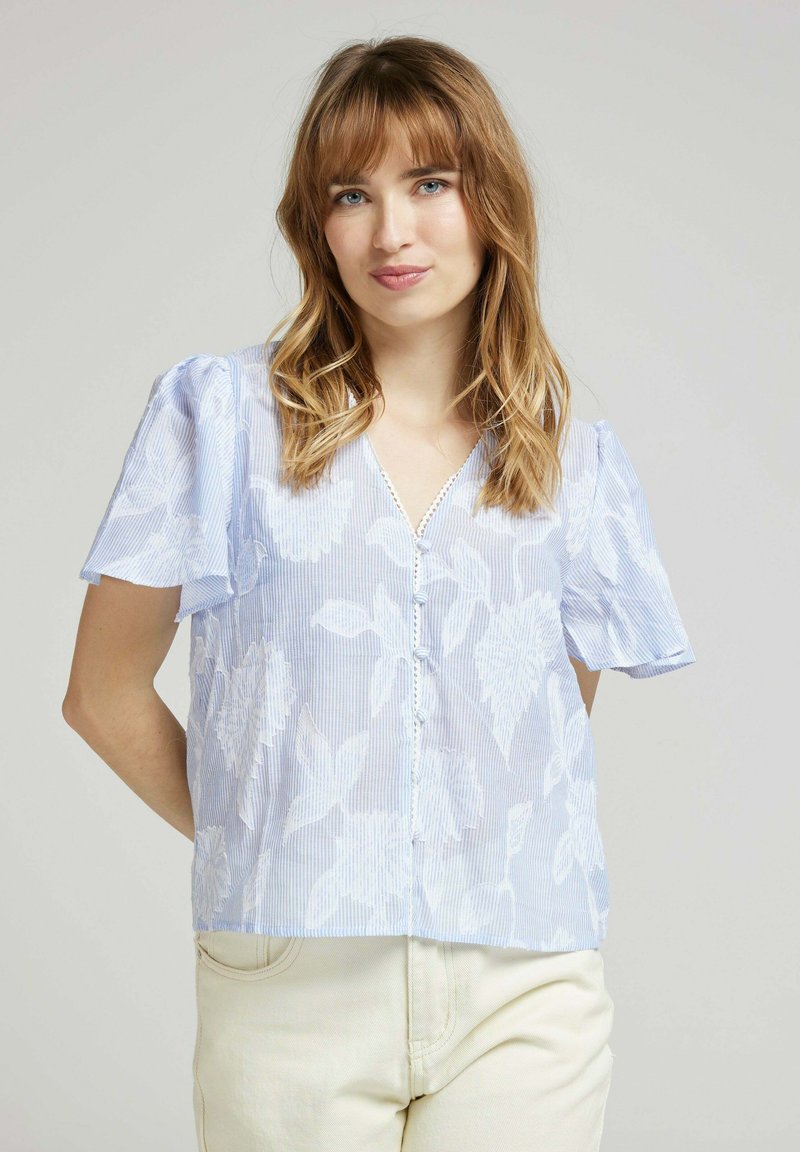 Blouse bleu clair à manches courtes avec motif floral, col en V et fermeture à boutons, en tissu doux et léger avec un léger motif rayé.