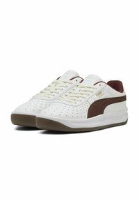Białe sneakersy z brązowymi akcentami, z perforowanym wzorem, okrągłymi sznurowadłami, wyściełanym kołnierzem i gumową podeszwą. Teksturowane panele boczne.