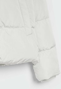 Chaqueta acolchada blanca con textura de costura, que presenta un acabado ligeramente brillante y un diseño de mangas ajustadas y entalladas. Sin hardware visible.