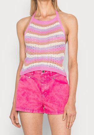 Femme portant un top sans manches rayé en tricot halter rose, beige, violet et blanc avec un short en denim taille haute rose vif.