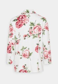 Biała kurtka z tkaniny w kwiatowy wzór, z dużymi różowymi różami, zielonymi liśćmi i kołnierzem; z długimi rękawami i otwartym przodem.
