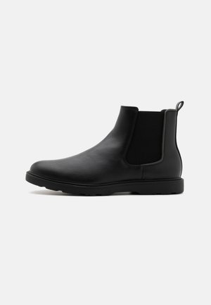 Botine Chelsea din piele neagră, cu panouri elastice laterale, cu bandă de prindere și un pantof cu talpă de cauciuc rezistentă. Textură netedă și design elegant.