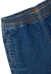 Pantalones de mezclilla azul con cintura elástica y costuras fruncidas, que presentan una textura suave y bolsillos laterales. Se pueden ver costuras reforzadas.