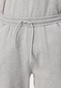 Grå joggebukser med snøring, ribbet livlinje og sidelommer. Laget av mykt, strukturert materiale for komfort.