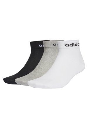 Trois paires de chaussettes de cheville en noir, gris et blanc. Chacune a un poignet côtelé et un logo de couleur contrastante sur la bande.