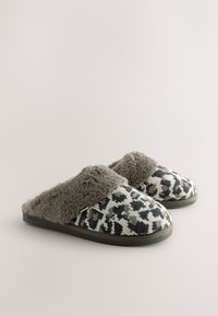 Chaussons à imprimé léopard avec une doublure en fourrure grise douce, dessus en textile, et une semelle extérieure robuste en caoutchouc noir. Ils présentent un design sans lacets pour un enfilage facile.