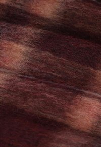 Tissu en laine présentant des tons chauds de bordeaux, de marron et de crème, avec une surface douce et texturée et de subtiles variations de couleur.