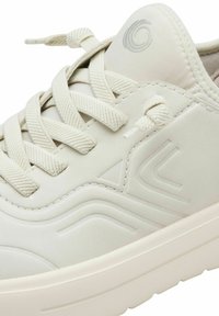 Sneakers grigio chiaro con tomaia sintetica texturizzata, lacci piatti e suola ammortizzata. Presentano elementi di design in rilievo e un logo sulla linguetta.