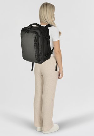 Zaino nero con tessuto texturizzato, presenta spallacci imbottiti, tasche laterali e chiusura a zip. Design rettangolare semplice, materiale resistente.