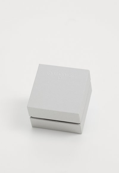 Small closed light gray square box with subtle embossed text "avgvst" on the top, placed on a plain white surface.