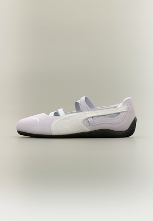 Zapato Puma estilo ballet plano en tonos lila claro y blanco con dos tiras elásticas y suela negra, mostrado de lado sobre un fondo neutro.