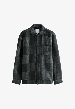 Mustavalkoinen ruudullinen takki, joka on valmistettu villamaisesta materiaalista. Takissa on kaulus, napit ja vasemmalla puolella tasku.