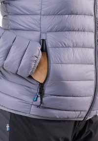 Light purple insulated jacket with a quilted design, featuring a zippered pocket and elastic cuffs. Material appears smooth and lightweight.