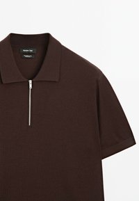 Polo shirt in misto lana marrone con colletto a zip e maniche corte. Il tessuto è liscio, con un colore uniforme senza motivi.