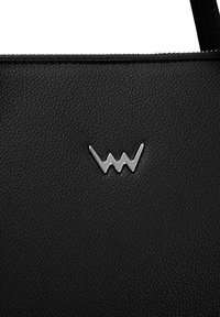 Schwarze grob strukturierte synthetische Lederhandtasche mit einem silbernen Logo, das ein Zickzackmuster auf der Vorderseite zeigt.