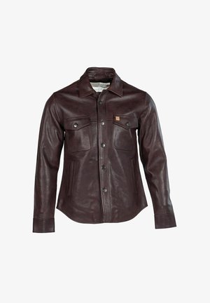 Brūna ādas jaka ar pogu aizdari priekšpusē, divām krūšu kabatām un smailu apkakli. Gluda tekstūra un nedaudz pieguļošs siluets.