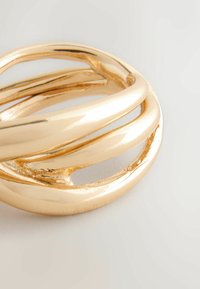 Kuldset tooni metallring, millel on keerdus disain sujuvate, läikivate pindade ja väljalõigatud osadega, luues abstraktse kihilise efekti.