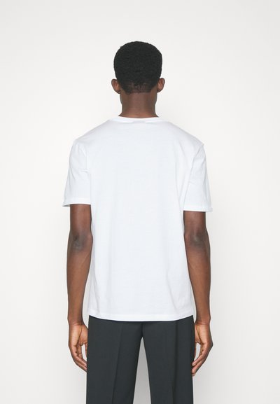 T-shirt en coton blanc à manches courtes, col rond et coupe décontractée. Présente un design uni, sans logos ni motifs visibles.