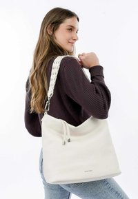 Borsa a spalla in pelle bianca con una finitura testurizzata, dotata di una fascia intrecciata e hardware argentato. Chiusura con cordoncino regolabile nella parte superiore.