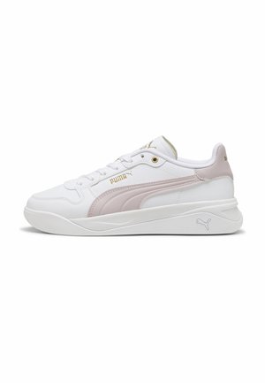 Biały sneaker Puma z jasnoróżowym paskiem, złotym logo Puma po boku i na języku oraz teksturowaną podeszwą, widziany od zewnętrznej strony.