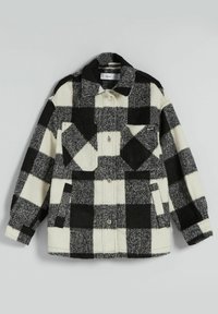 Svart och vit rutigt jacka gjord av tjockt, texturerat tyg; har två bröstfickor, en krage och knappstängningar.