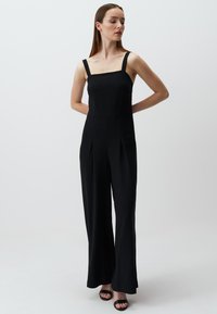 Zwarte jumpsuit met vierkante halslijn, breed been ontwerp, geplooide voorkant en smalle schouderbanden. Gladde stof en minimalistische esthetiek.