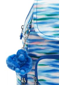 Blå och grön mönstrad ryggsäck med en lurvig blå apa nyckelring fäst. Har en dragkedjestängning och justerbar rem.