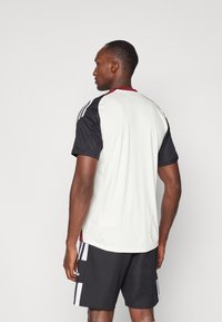 Korte mouwen sportshirt in het wit met zwarte mouwen, met een rode kraag en drie zwarte strepen op elke schouder.